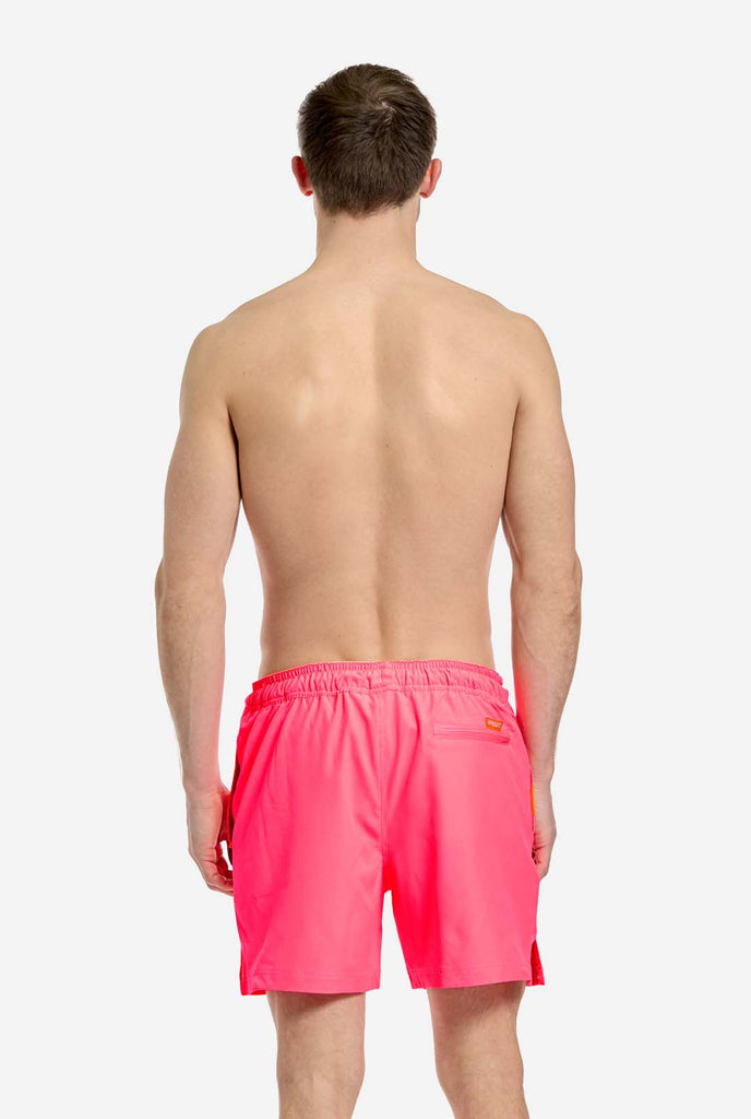 Man wearing Neon Pink Power swim trunks for men, view from the back