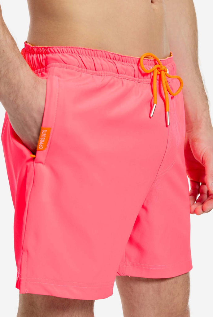 Man wearing Neon Pink Power swim trunks for men, close up