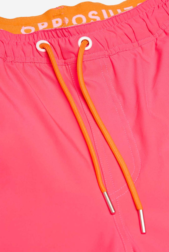 Man wearing Neon Pink Power swim trunks for men, close up