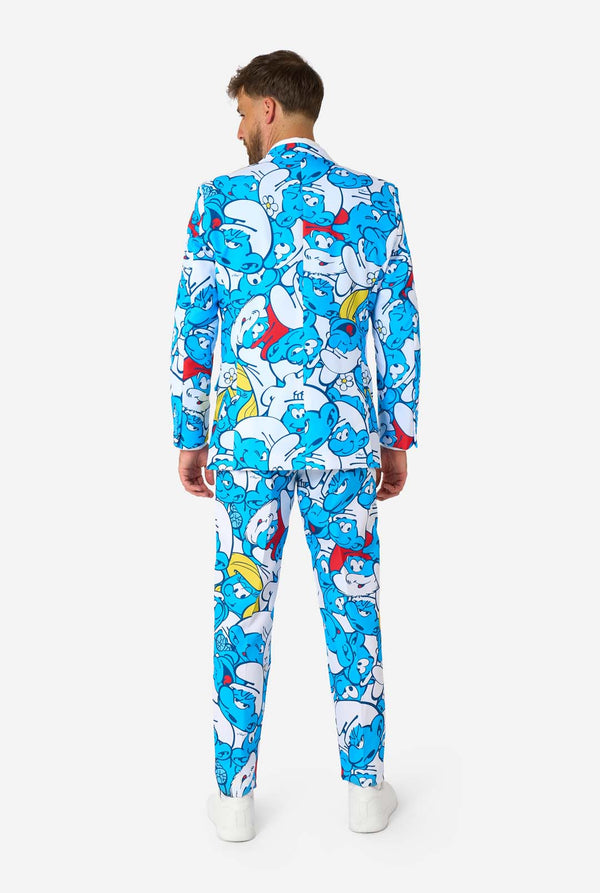Man wearing a colorful Smurfs men's suit with an all-over cartoon print in blue, white, red, and yellow, including a matching tie and white shirt, standing against a plain background. View from the back.