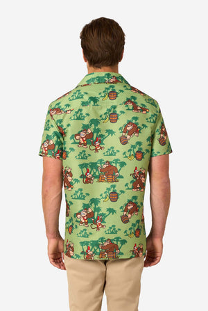 Image of a man wearing a Donkey Kong themed Hawaiian shirt. The shirt has a light green background and contains dark green palm trees, and multiple images of the character Donkey Kong, from Super Mario. View from the back.