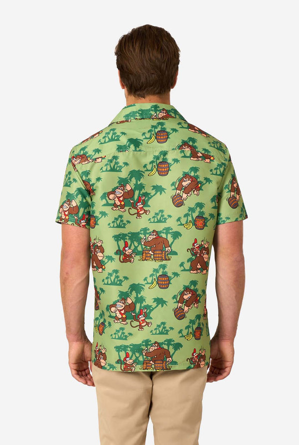 Image of a man wearing a Donkey Kong themed Hawaiian shirt. The shirt has a light green background and contains dark green palm trees, and multiple images of the character Donkey Kong, from Super Mario. View from the back.