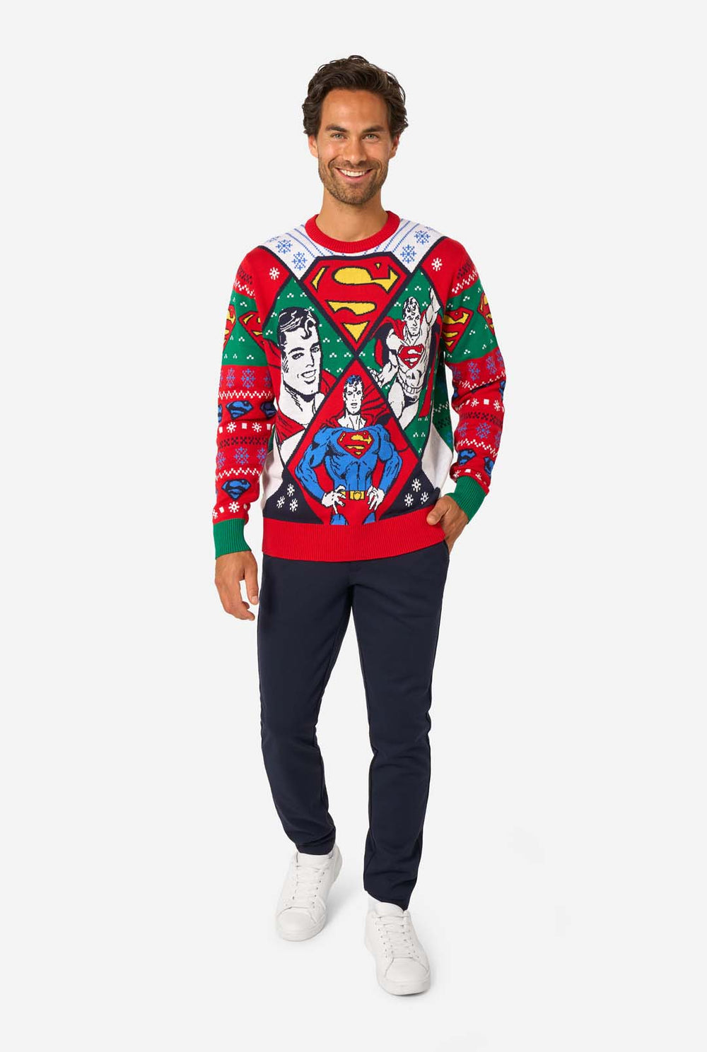 Man wearing a colorful knitted Christmas sweater featuring multiple Superman designs and the iconic “S” logo.
