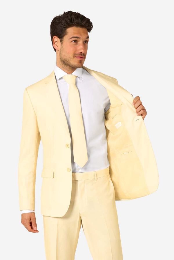 Elegant men's suit in a soft pastel yellow shade, perfect for weddings, summer events, and formal occasions. This stylish tailored suit features a slim fit design, notch lapels, and a matching tie for a sophisticated look. Ideal for modern gentlemen looking to make a statement with a light-colored pastel suit. Holding one side of the blazer open.