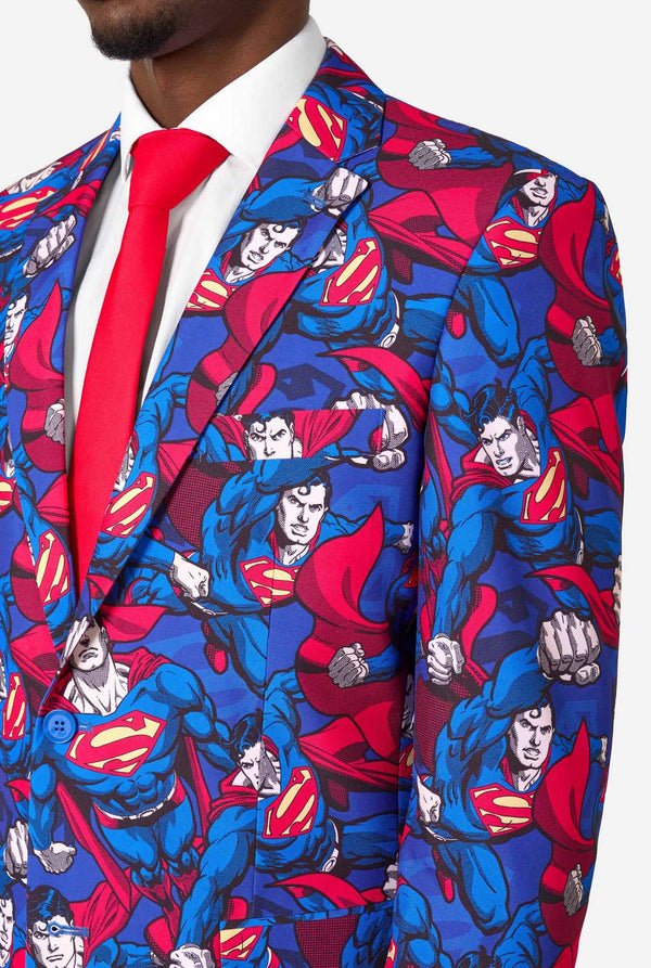 A man wearing a Superman themed suit with a red tie and a white shirt on a white background. Close up of the chest