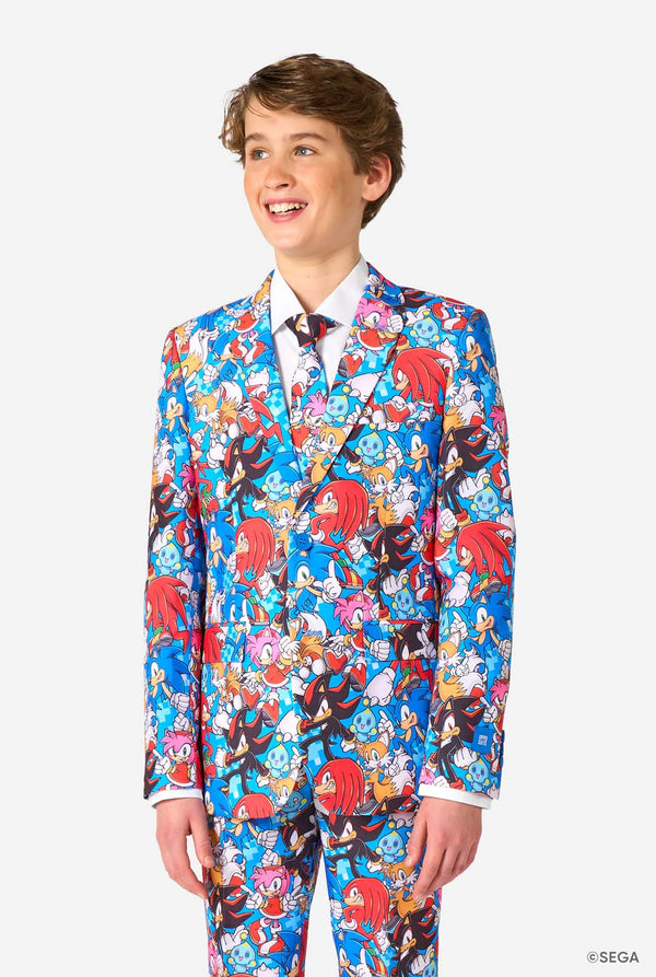 Teen boy wearing a vibrant Sonic teen suit featuring colorful prints of Sonic the Hedgehog characters including Sonic, Knuckles, Tails, and Amy, paired with a matching tie and white shirt.