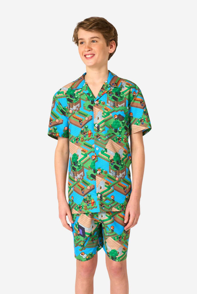 A Teen boy wearing a colorful summer outfit featuring a Minecraft Overworld print, showcasing pixelated landscapes, characters, and elements from the iconic game. The short-sleeve shirt and matching shorts highlight a vibrant design inspired by the Minecraft universe. 