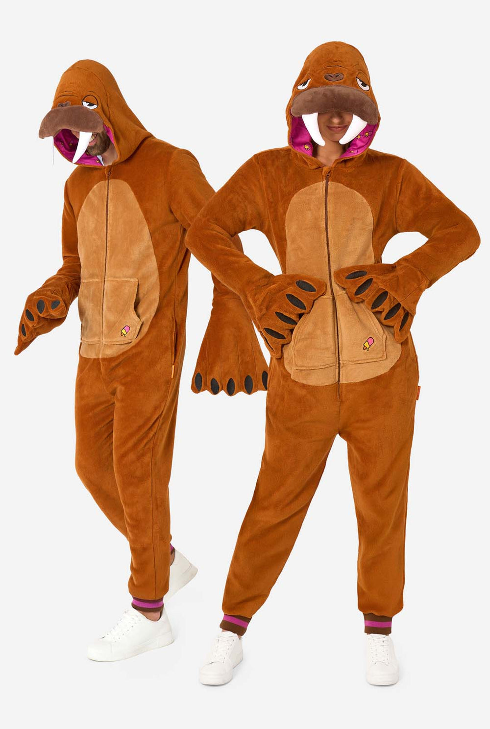 A cheerful man and women are wearing a brown adult onesie designed as a walrus. The onesie features a hood with fangs, stitched gloves resembling paws, and playful walrus details, perfect for cozy lounging or costume parties. The hood are on their heads.