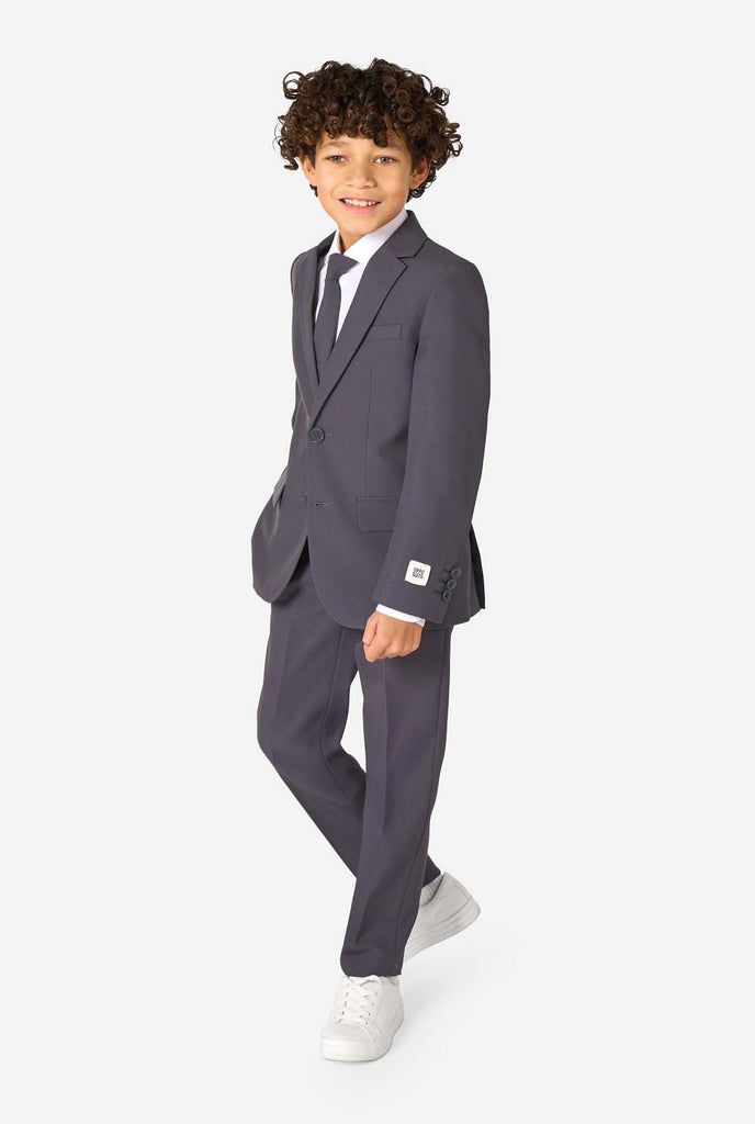 Kid wearing a stylish charcoal colored grey suit with a white dress shirt, smiling confidently. Perfect formal outfit for boys' special occasions, weddings, and parties. Full body image.