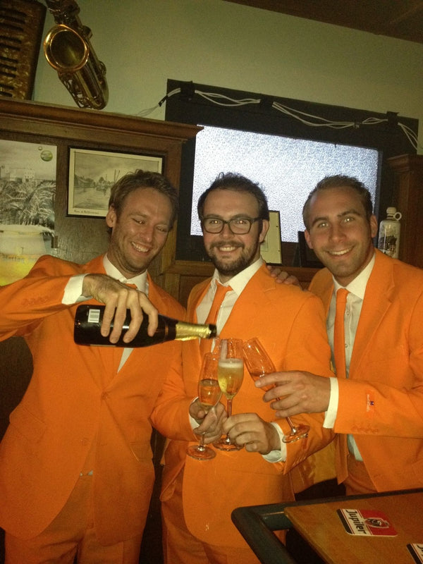 An image of the 3 founders of Opposuits wearing a orange suit, drinking champagne.