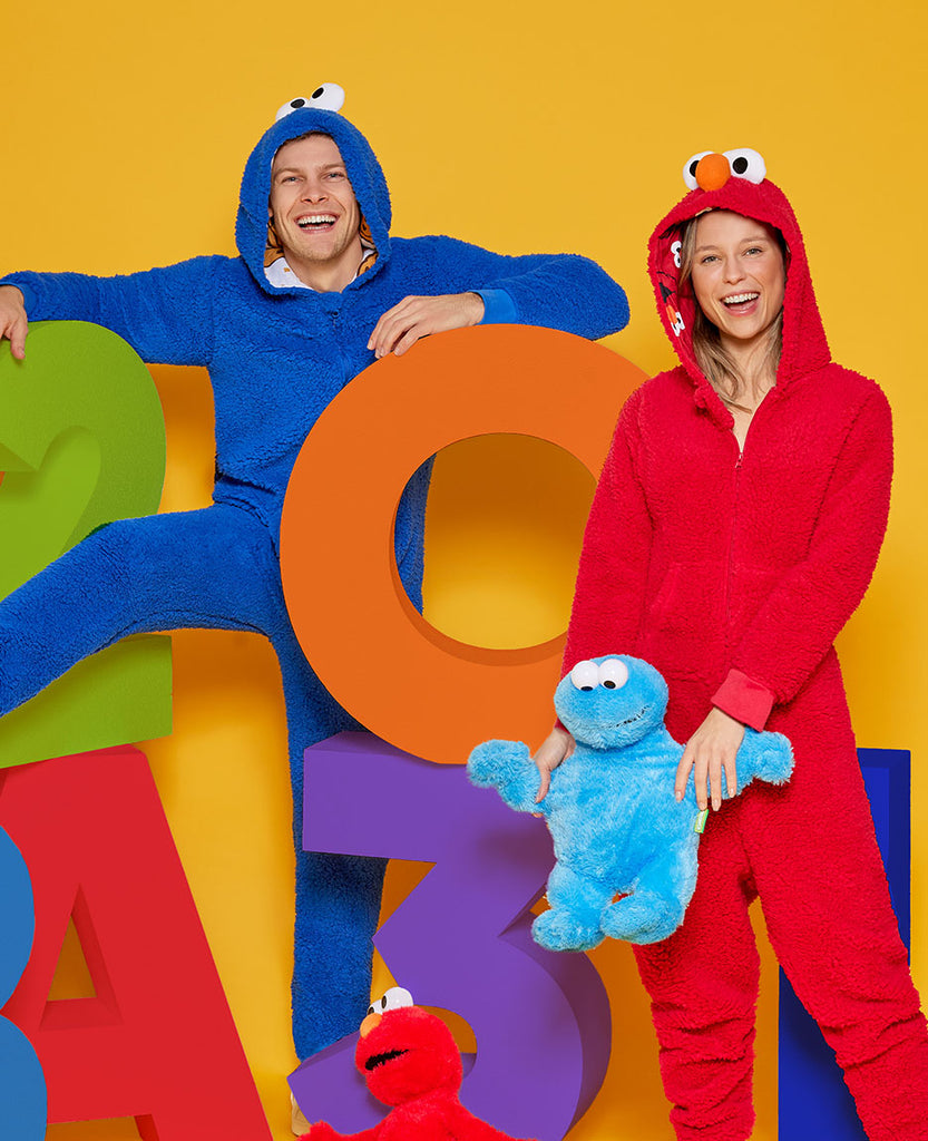 Man wearing Cookie Monster Onesie en woman wearing Elmo onesie.