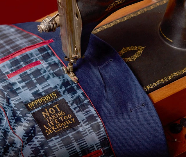 An image of a sewing machine, sewing a Opposuits Deluxe jacket.